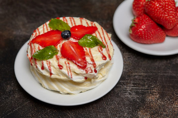 White creamy round cake with strawberries and mint on plate
