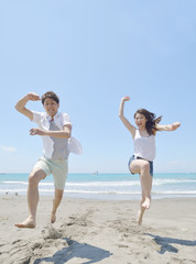 ビーチでジャンプする若いカップル