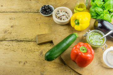 Fresh vegetables with olive oil, herbal salt and pesto on a cutting board