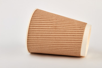 Empty paper cup lying on white. Brown ripple paper container isolated.