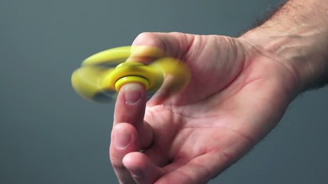 Yellow fidget spinner in male hand, selective focus