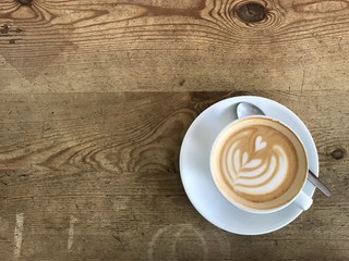 Top view latte art heart pattern on top of cappuccino which on old rough wood table background