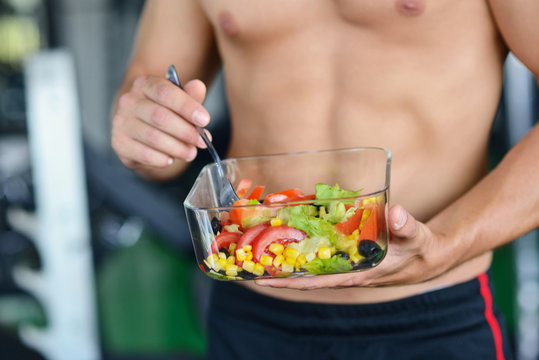 Powerful athletic man with great physique eating a healthy salad.