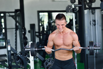 Fototapeta na wymiar Man at the gym. Man makes exercises with barbell