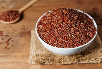 Rice berry in white bowl on wooden background