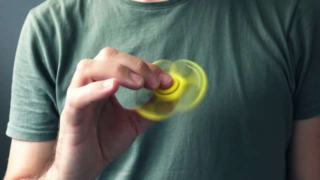 Yellow fidget spinner in male hand, selective focus