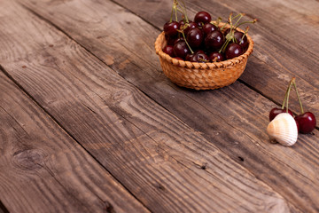 Cherries in a basket on gray wooden boards