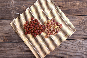 Photo of pistachios peeled from shell and hazelnuts lying on a mat on gray, old boards, top view.