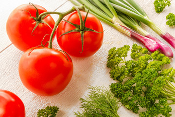 Fresh juicy vegetables tomatoes, parsley, onion ingredients for salad cooking, vegetarian dishes, the concept of proper healthy dietary nutrition