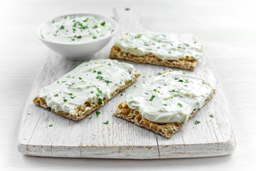 Homemade Crispbread toast with Cream Cheese and parsley on white wooden board background.