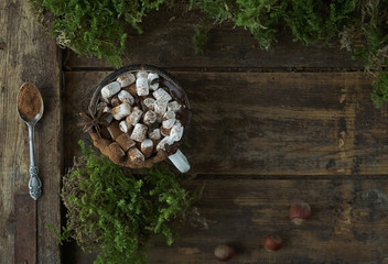 Christmas delicious hot chocolate with marshmallows, nuts and cinnamon on wooden background, top view