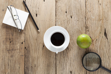white coffee cup with business objects on old wooden table.