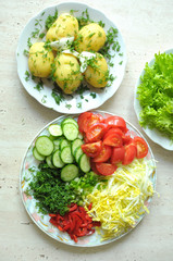 Fresh organic vegetables and boiled new potatoes on three plates