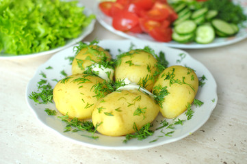 Fresh organic vegetables and boiled new potatoes on the plates