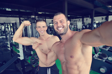 Fototapeta na wymiar Portrait of two smiling muscular men flexing biceps