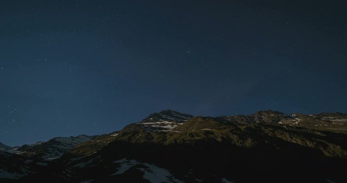 The apparent rotation of the starry sky and the full moon over the majestic Italian Alps, under bright moonlight. Time Lapse