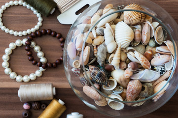 Bowl of seashells with pearls, beads and thread nearby