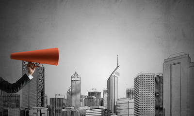 Hand of businesswoman holding red paper trumpet against cityscape background