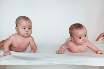 Two funny twin babies lie on their tummy. Boy and girl.