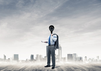 Camera headed man standing on wooden floor against modern citysc