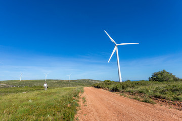 un paysage avec des éoliennes sur le chemin de crête d'une colline et un homme en chemise blanche et cravate et son cartable