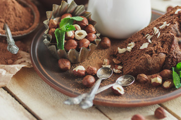 Piece of chocolate cake, mint leaves, hazelnuts and jar with milk
