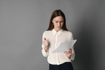 Businesswoman holds the papers in her hands and reads what is written there. Isolated on gray background.