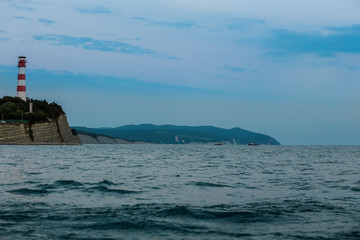 Lighthouse in the sea coast. Calm blue sea and lighthouse on the horizon. Sea horizon