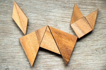 Tangram puzzle in cat shape on wooden background