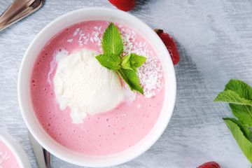 Cold creamy strawberry soup with a scoop of ice cream and mint