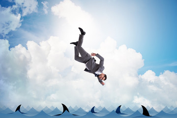 Businessman falling into sea with sharks