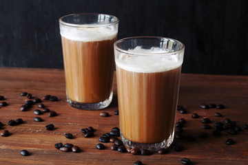 two glasses of coffee with ice cream on a table against a  black wall