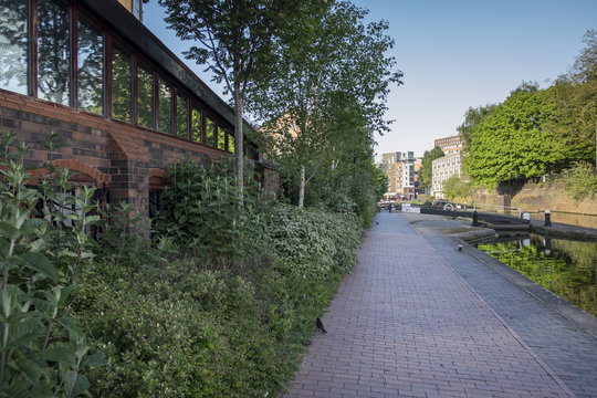 Canal path in Birmingham city centre, in the summer, with plentiful green foliage growing along the path
