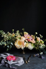 Obraz na płótnie Canvas Wedding decor, Pink peony on silk napkins and flower arrangement on a dark background, Wedding bouquet, Decorator, Copy Space, Selective focus