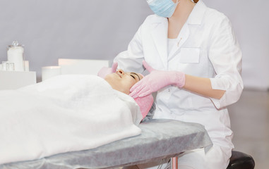 Beautician performs cosmetic procedures and applying cream in Cosmetology clinic