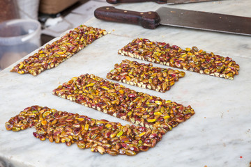 Freshly made pistachio nut brittle on a street stall in Cannaregio, Venice, Italy where one could watch the vendor making it with focus to the centre piece