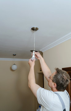 Electrician is installing a LED bulb.