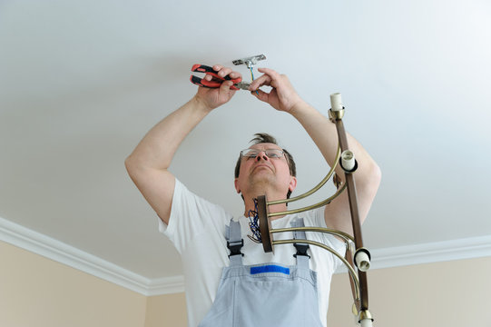 Electrician is installing and connecting a lamp.