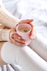 Woman with cup of coffee sitting on the bed