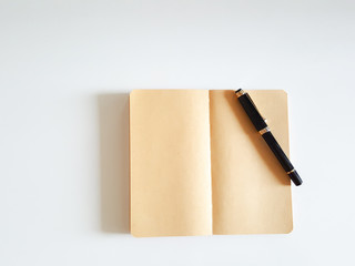 Top view open notebook and pen on white desk background.