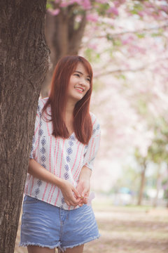 Happy woman traveler relax feel free with cherry blossoms or sakura flower tree on vacation