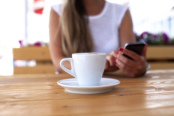 Young woman texting on the phone in a cafe