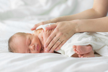 Fototapeta na wymiar Newborn baby sleeping on a blanket. Mother gently strokes her child's hand
