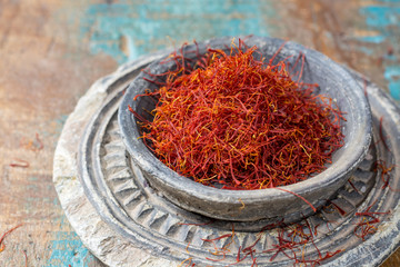Fototapeta premium Dried organic red saffron Spice in a stone bowl on wooden background