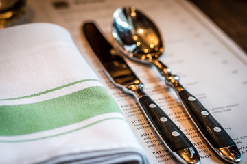 Knife and spoon cutlery and linen napkin menu on table
