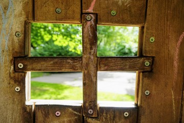 Holzfenster von Innen mit Blick nach draußen auf einem Spielplatz