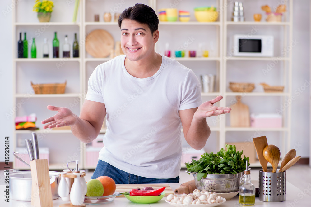 Wall mural young male cook working in the kitchen