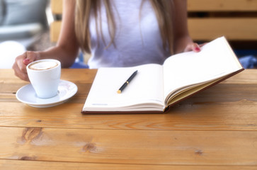Young woman in cafe with notebook and espresso