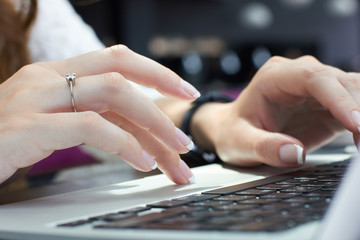 Cropped image of young woman hands typing on laptop computer in coffee shop. Business woman using laptop computer.Freelance concept.