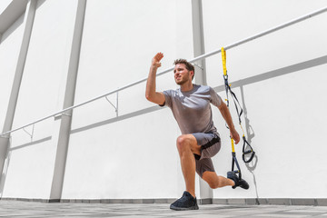 Fitness suspension straps man training legs with suspended lunge exercise at gym. Lower body...